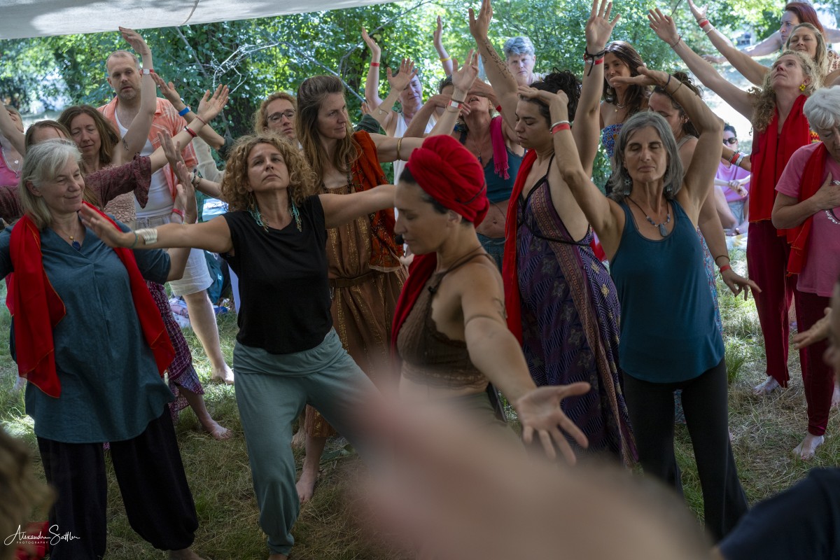 Participants dansant les bras levés sous les arbres au Festival Mantra Joie.